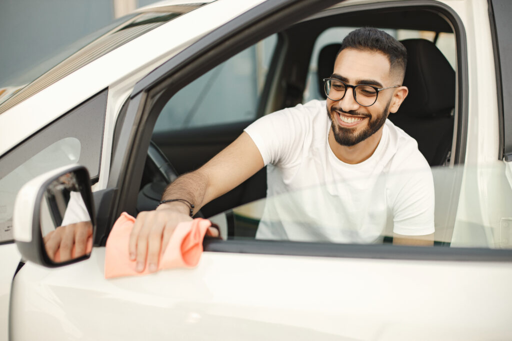 indian man polishing inside his white car with a rug